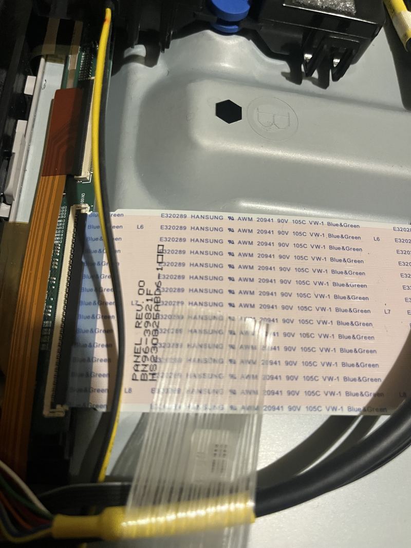 A close-up of the ribbon cables running into a television's panel driver board, with the panel's own part number printed along the cable.
